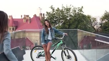 Bisikletli çekici genç kız, en iyi kız arkadaşı için şehir caddesinde özel donanımlı bir meydanda buluşuyor.