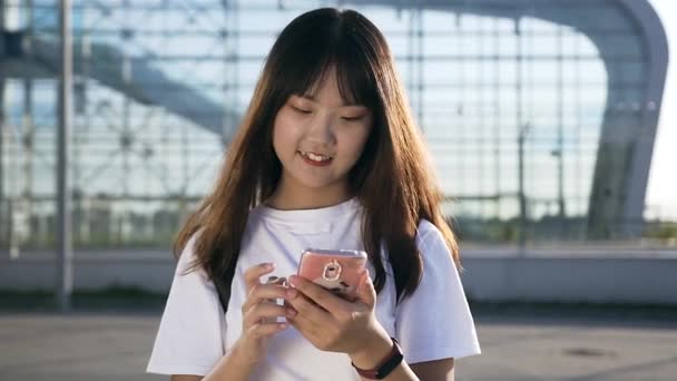 Aantrekkelijk portret van jonge Aziatische aangename vrouw wandelen met smartphone in de buurt van moderne luchthaven — Stockvideo