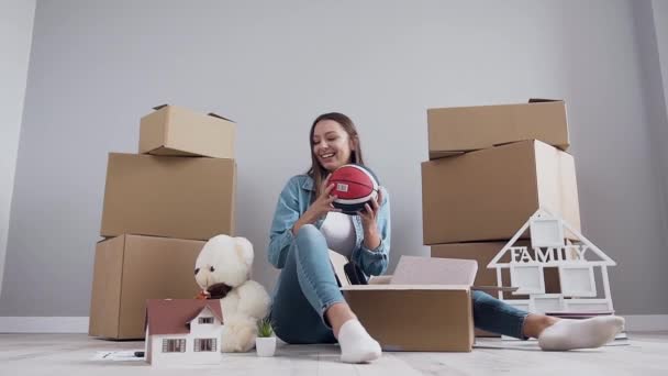 Alegre agradável 30-aged menina se divertindo sozinho ao desempacotar caixa após realocação em seu novo apartamento comprado — Vídeo de Stock