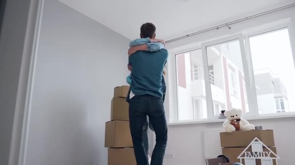 Usmívající se pohledný muž krouží v náručí její šťastný rozkošný žena v jejich novém bytě po relokaci — Stock video