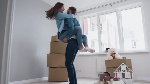 Apelando casal feliz comemorando a mudança para o novo apartamento entre diferentes caixas — Vídeo de Stock