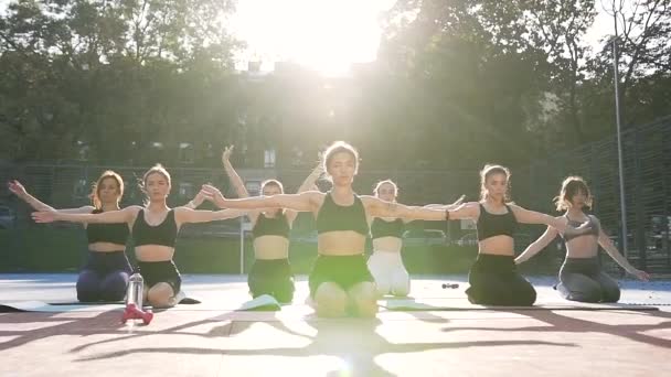 Frontansicht eines weiblichen Fitnessteams, das beim Sport-Workout auf dem Sportplatz im Park kniet und entspannende Übungen macht — Stockvideo