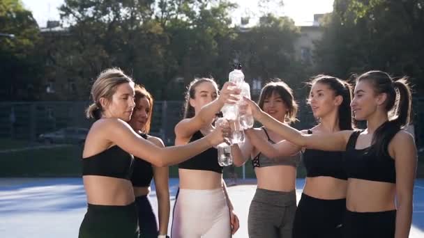 Fitness vrouwelijke groep geven high five met flessen en drinkwater na sport coaching op het buitenstadion — Stockvideo