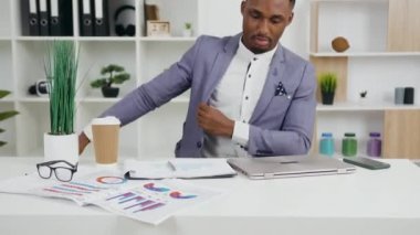 Çekici, genç, şık, Afro-Amerikan ofis çalışanı iş yerine kahve ile yaklaşıyor, oturuyor ve dizüstü bilgisayarla çalışmaya başlıyor, 4K