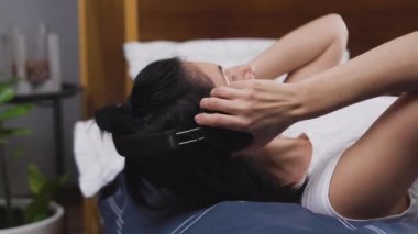 Modern müzik dinlemek için yatağa uzanan ve kulaklık takan iyi huylu, genç esmer