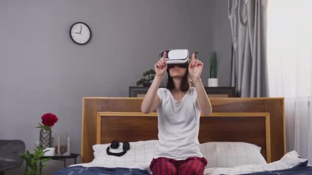 Visão frontal de morena jovem muito focada e ocupada que trabalha na tela interativa usando fone de ouvido de realidade virtual em casa — Vídeo de Stock