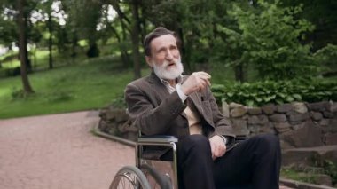Çekici, rüya gibi sakallı, son sınıf öğrencisi. Parkın ortasında tekerlekli sandalyede oturuyor ve sigara içiyor. Sessizliğin tadını çıkarıyor.