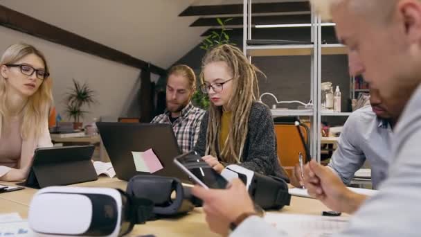 Considerável grupo diversificado de homens e mulheres que se sentam à mesa do escritório e trabalham juntos no âmbito de um projecto empresarial — Vídeo de Stock