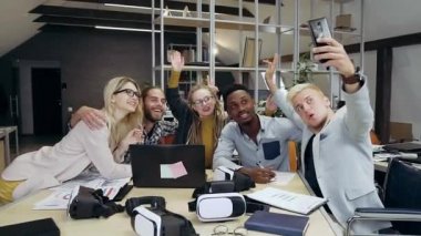 Çekici gülümseyen başarılı ofis çalışanları çağdaş ofis odasında çalışırken selfie çekiyorlar. Kapatın.