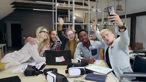Attraktive lächelnde erfolgreiche junge Büromenschen, die Selfies machen, während sie gemeinsam im modernen Büroraum arbeiten, aus nächster Nähe — Stockvideo
