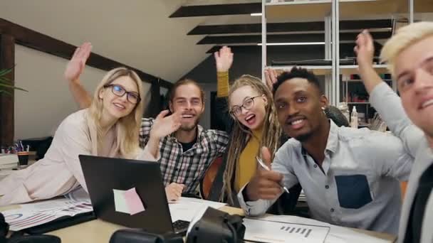 Добродушные довольные умные стильные молодые международные коллеги делают фотографии на мобильном телефоне, сидя в современной офисной комнате — стоковое видео