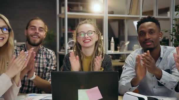 Vista frontale di simpatici sorridenti persone d'ufficio multietniche altamente qualificate che siedono nell'ufficio contemporaneo e battono le mani mentre posano nella fotocamera — Video Stock