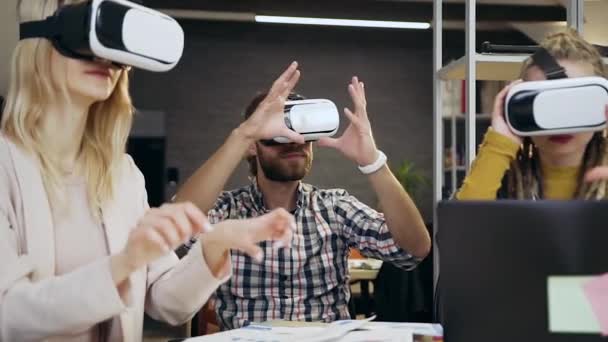 Sympathisch rücksichtsvoll erfahrene junge moderne Firmenmitarbeiter, die gemeinsam in einem Virtual-Reality-Headset im modernen Büroraum arbeiten — Stockvideo