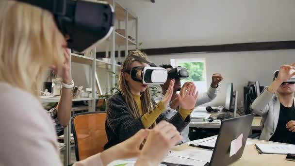 Close-up van geconcentreerd aantrekkelijk creatief divers team van kantoormedewerkers die in het kader van een gezamenlijk project werken met een virtual reality-headset binnenshuis — Stockvideo