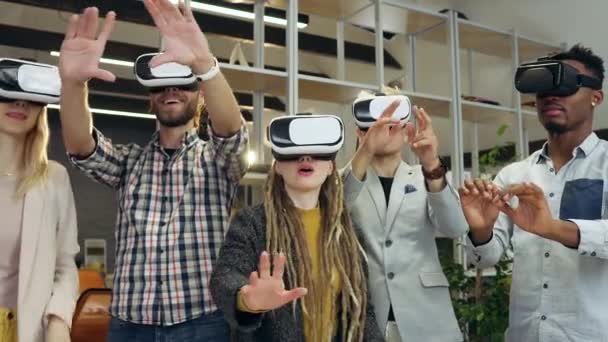 Gros plan de bons collègues internationaux expérimentés et concentrés qui travaillent sur écran imaginaire à l'aide d'un casque de réalité virtuelle dans une salle de bureau contemporaine, 4k — Video