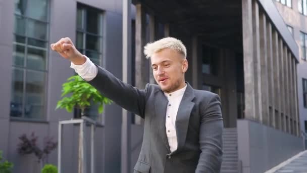 Närbild av sympatisk glad 30-årig blond man i elegant slitage som har kul på elektrisk skoter utomhus på solig dag — Stockvideo