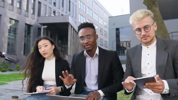 Mouvement lent de jeunes amis heureux heureux heureux agréables qui montrent signe OK dans la caméra pendant le travail en plein air avec ordinateur, tablette pc et rapports financiers — Video