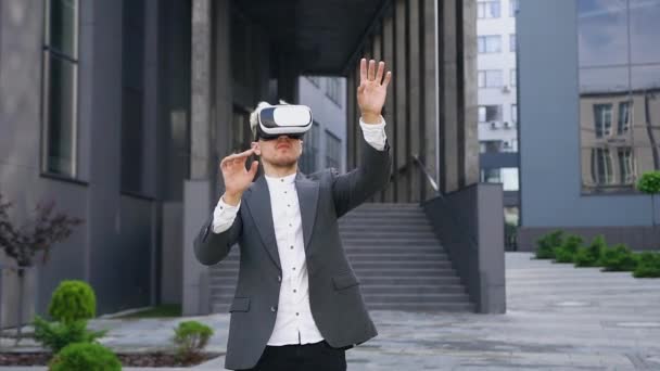 Långsam rörelse av attraktiva allvarliga målmedveten smart ung man i särskilda skyddande 3D-glasögon som arbetar på virtuell skärm utomhus — Stockvideo