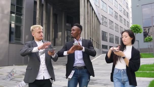 Good-looking happy contented cheerful international office workers scattering money and dancing while celebrating win after successful ending of joint project — Stock Video