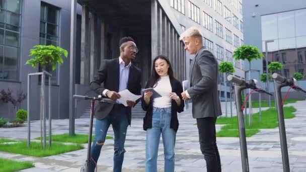 현대 사무실 건물 근처에서 서류와 대마 타블렛을 가지고 일하는 유쾌 한 인종 집단젊은 사무원들의 모습 , 4k — 비디오