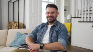 Tekerlekli sandalyedeki yakışıklı, mutlu, sakallı adam. Arka planda şanslı bir gülümsemeyle kameraya bakıyor.