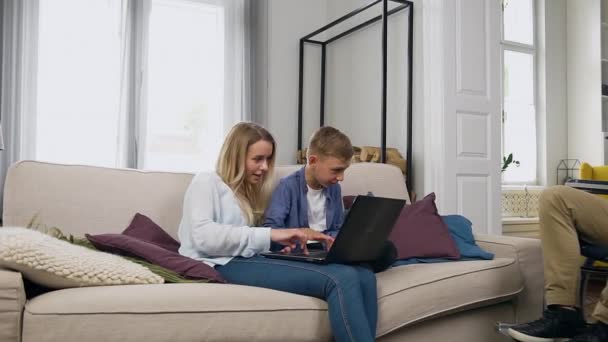 Joyeux joyeux heureux jeune mère appliquant ordinateur portable avec son beau fils souriant à la maison quand beau père barbu positif en fauteuil roulant se joignant à eux — Video