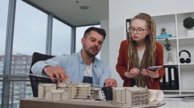 Kendine güveni yüksek, sakallı genç bir mimar. Cetvelle ölçülüyor. Modellik ve radarlı bir kadın.
