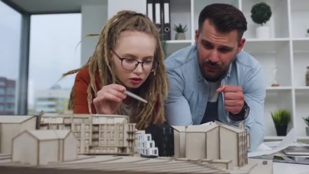 Πορτρέτο ελκυστικών δημιουργικών έξυπνων έμπειρων νέων σχεδιαστών που συζητούν το ξύλινο μοντέλο των μελλοντικών κτιρίων στο σύγχρονο αρχιτεκτονικό γραφείο, 4k — Αρχείο Βίντεο
