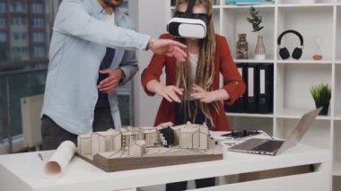 Çekici, yüksek yetenekli, konsantre 35 'li yaşlarda başarılı tasarımcılar, modern tasarım stüdyosuna özel 3D gözlükler takan ahşap bina modeliyle çalışıyorlar.