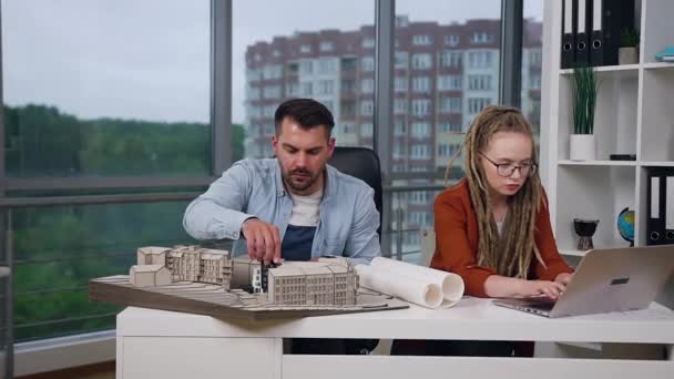 Close view of likable concentrated modern high-skilled male and female colleagues which working together with model of new buildings in design office in daytime — Stock Video