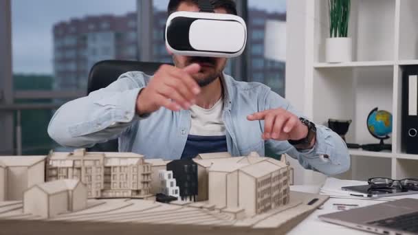 Jolie créatrice professionnelle jeune ingénieur-designer barbu en réalité virtuelle casque travaillant avec le modèle des futurs bâtiments dans le studio de design — Video