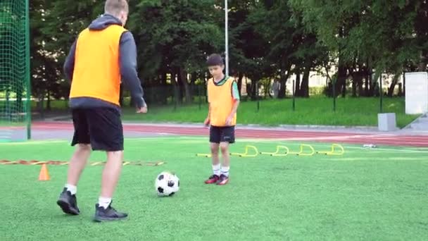 Portrait of concentrated sporty asian teen boy which training together with his experienced young football trainer on the outdoors sport ground on sunny day,4k — Stock Video