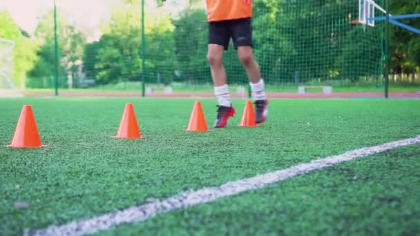 Anak remaja yang sporty melakukan latihan lari dengan rak-rak yang ditempatkan pada satu garis untuk meningkatkan kualitas kecepatannya selama pelatihan sepak bola di lapangan olahraga luar ruangan — Stok Video