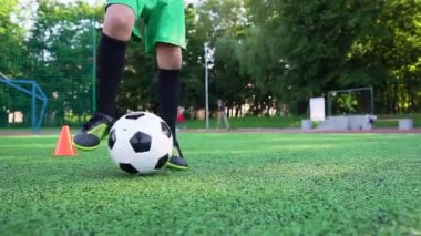 Güneşli bir günde spor sahasında antrenman yaparken futbol becerileri ve top numaraları uygulayan çocukların ayaklarını kapatın.