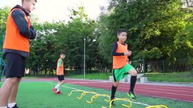 Deneyimli genç koçun komutası altında, stadyumda engellerle koşan, sürekli çalışan 13 'lü futbolcuların portresi.