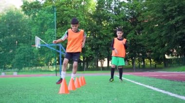 Spor giyim üzerine yoğunlaşmış genç futbol oyuncuları güneşli bir günde futbol sahasında antrenman yaparken egzersiz yapıyorlar.