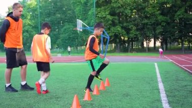 Kendilerine güveni tam genç futbolcuların ön görüntüsü. Spor sahasında askılarla atlama egzersizleri yapıyorlar. Başka bir antrenörün gözetimi altında özel yeşil kaplamalı.