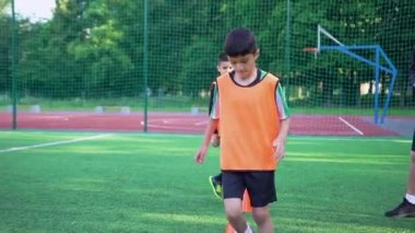 Futbol formalı kendinden emin gençlerin, antrenman günü stadyumda engelli koşma egzersizleri yapmasının ön görüntüsü.