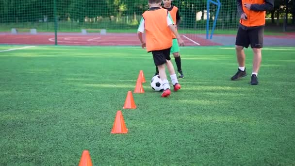 Çekici kendine güvenen genç futbol oyuncuları sahada top oynayarak spor yapıyorlar ve sırayla açık stadyumda koşuyorlar. — Stok video