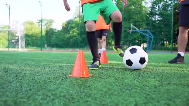 Concepto de fútbol donde joven enérgico en uniforme de fútbol entrenamiento con pelota alrededor de pequeños bastidores para mejorar su velocidad durante el entrenamiento en el campo de fútbol — Vídeos de Stock