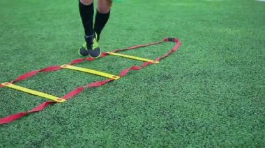 Spor sahasındaki antrenman sırasında futbol merdivenlerinde koşu yapan ve zıplayan erkek ayaklarının fotoğraflarını çek.