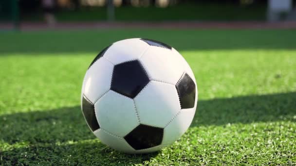Primer plano de la pelota de fútbol que se encuentra en la cubierta verde especial mientras que el jugador masculino o femenino irreconocible patadas hacia la puerta — Vídeos de Stock