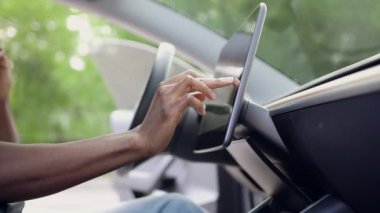 Meçhul Afrikalı Amerikalı kendi arabasının gidonunun önünde telefonla konuşuyor ve GPS kullanıyor.