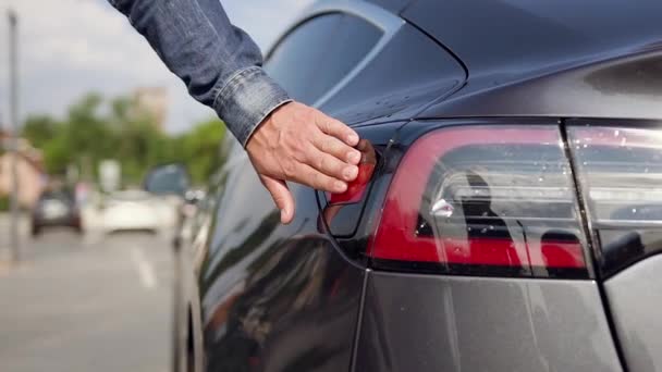 Zbliżenie dłoni człowieka, który otwiera miejsce ładowania samochodów w celu tankowania energii elektrycznej na stacji benzynowej — Wideo stockowe