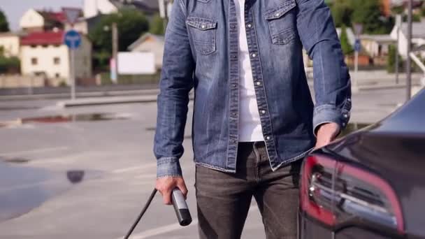 Attractive young bearded modern guy charging his trendy electric car at specially-equipped charging station — Stock Video