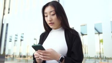 Çekici, gülümseyen, Asyalı görünümlü, toplu taşıma aracında durup cep telefonunu kullanan esmer bir kızı yakından çek.