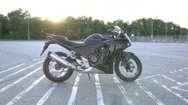 Spor sahasında güneş ışığı altında duran pahalı siyah motosikletlere yakın durun.