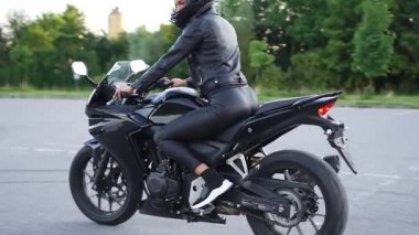 Gösterişli, ince, şık, koruyucu kasklı, motosikletli, mototrack 'te spor motosikletli genç bir kadın.
