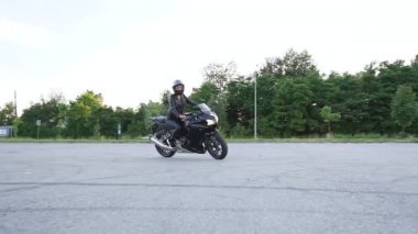 Güzel, kendine güvenen, zarif, koruyucu kasklı, siyah elbiseli, mototrack 'te siyah spor motosiklet süren genç bir kadın.