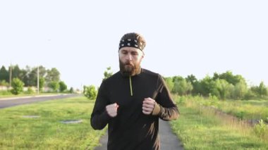 Çekici, konsantre, genç, sakallı boksör sabahları koşu egzersizleri yapıyor ve dışarıda yumruk pratiği yapıyor.